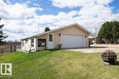 Exterior featuring light-toned vinyl siding, a prominent two-car garage, and a side sunroom with multiple windows - 27132A Twp Rd 632, Rural Westlock County, AB - Outdoor