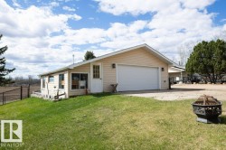 Exterior featuring light-toned vinyl siding, a prominent two-car garage, and a side sunroom with multiple windows - 