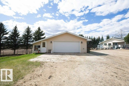 Detached garage with beige siding, white garage door, and exterior lighting fixtures - 27132A Twp Rd 632, Rural Westlock County, AB - Outdoor