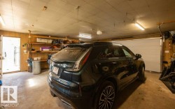 Attached garage featuring a white sectional door, wood-paneled walls, and built-in shelving - 