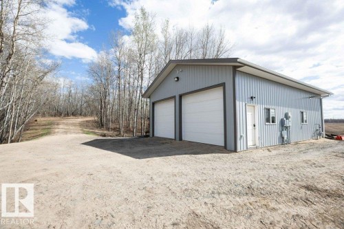 Gray metal-sided outbuilding featuring two white garage doors, a side entry door, and multiple windows - 27132A Twp Rd 632, Rural Westlock County, AB - Outdoor With Exterior