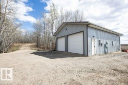 Gray metal-sided outbuilding featuring two white garage doors, a side entry door, and multiple windows - 