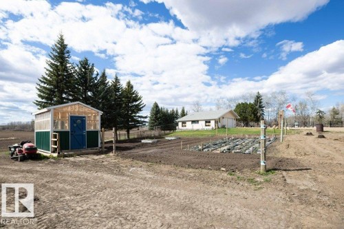 Property features a large, cleared lot with a separate shed structure, a planted garden area, and mature evergreen trees - 27132A Twp Rd 632, Rural Westlock County, AB - Outdoor