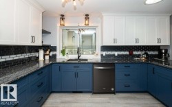 Kitchen featuring white upper cabinetry, blue lower cabinetry, and black hardware - 