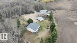 Expansive property featuring a main residence with a gray shingle roof, accompanied by a detached garage and an additional outbuilding - 