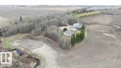 Rural property with a residential structure, detached outbuilding, and extensive surrounding agricultural fields - 