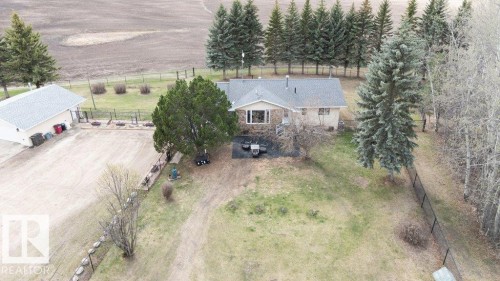 Ranch-style residence featuring a stone and stucco exterior, an attached garage, a detached garage with a light grey shingle roof, and surrounding mature trees - 27132A Twp Rd 632, Rural Westlock County, AB - Outdoor With Deck Patio Veranda