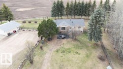 Ranch-style residence featuring a stone and stucco exterior, an attached garage, a detached garage with a light grey shingle roof, and surrounding mature trees - 