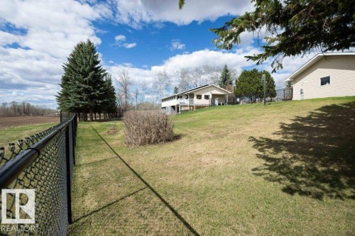 Expansive fenced yard featuring a sloped lawn, mature evergreen trees, and partial views of surrounding fields - 27132A Twp Rd 632, Rural Westlock County, AB - Outdoor