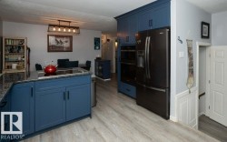 Modern kitchen featuring blue cabinetry, dark countertops, and wood-finish flooring - 