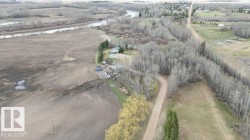 Expansive land parcel featuring multiple structures, cleared agricultural fields, and a river frontage - 