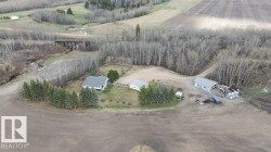Rural property featuring a main residence, secondary building, and large outbuilding, surrounded by cultivated fields and mature trees - 