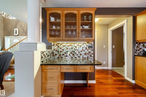 Kitchen area with wood cabinetry, glass-front upper cabinets, and a granite countertop - 4 Windrose Drive, Leduc, AB - Indoor Photo Showing Other Room