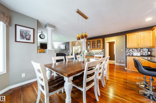The property features hardwood floors throughout the dining area and kitchen, complemented by light wood cabinetry and a tiled backsplash in the kitchen - 4 Windrose Drive, Leduc, AB - Indoor Photo Showing Dining Room