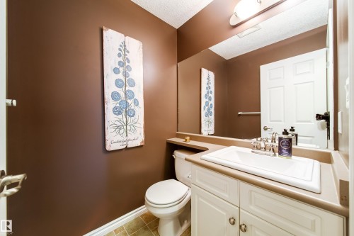 Bathroom featuring a vanity with a white sink, a mirror, and a toilet - 4 Windrose Drive, Leduc, AB - Indoor Photo Showing Bathroom