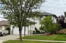 The property features a two-car garage, a well-maintained lawn, and mature trees - 4 Windrose Drive, Leduc, AB  - Outdoor 