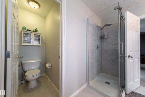 The bathroom features a glass-enclosed shower with subway tile, a toilet, and a wall-mounted storage cabinet - 4 Windrose Drive, Leduc, AB - Indoor Photo Showing Bathroom