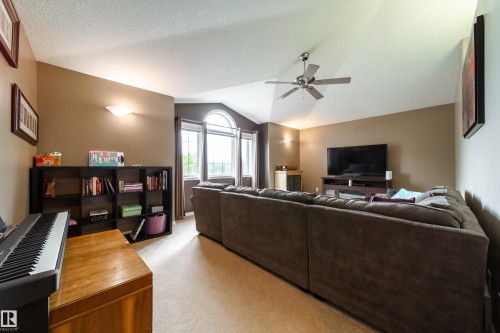 Spacious living area featuring vaulted ceilings, a ceiling fan, and large windows with an arched top providing natural light - 4 Windrose Drive, Leduc, AB - Indoor Photo Showing Living Room