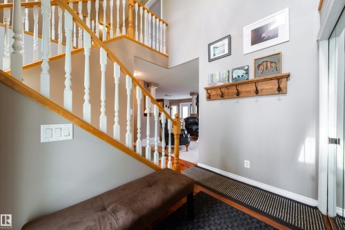 Inviting entryway featuring a wooden staircase with white balusters, a wooden coat rack, and light gray walls - 4 Windrose Drive, Leduc, AB - Indoor Photo Showing Other Room