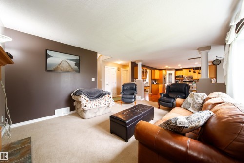 This living area features a spacious layout with light-colored carpeting, a dark accent wall, and decorative columns - 4 Windrose Drive, Leduc, AB - Indoor Photo Showing Living Room