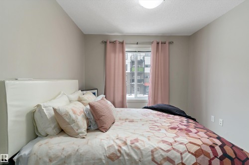 Neutral tone walls framing a window with light-filtering curtains - 221 344 Windermere Road, Edmonton, AB - Indoor Photo Showing Bedroom
