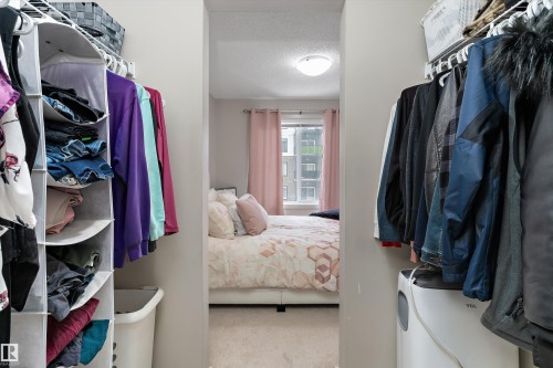 Walk-through closet with built-in wire shelving and a soft carpeted bedroom area - 221 344 Windermere Road, Edmonton, AB - Indoor With Storage