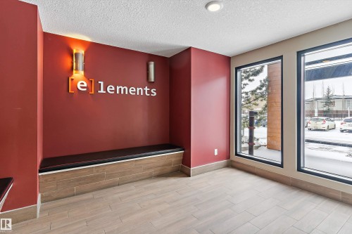 Entryway featuring a built-in bench with dark upholstery, sconce lighting, and large windows - 221 344 Windermere Road, Edmonton, AB - Indoor Photo Showing Other Room
