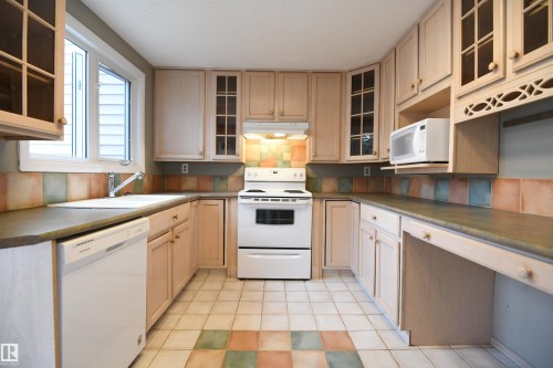 The shaker maple kitchen has loads of cabinet and counter space, and matches the extra cabinetry in the dining area.  Glass doors, ceramic tile, a writing desk, as well as an additional access to the rear yard and deck - 6706 36A Avenue, Edmonton, AB - Indoor Photo Showing Kitchen