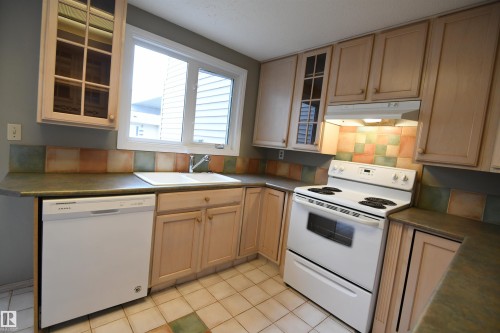 The shaker maple kitchen has loads of cabinet and counter space, and matches the extra cabinetry in the dining area.  Glass doors, ceramic tile, a writing desk, as well as an additional access to the rear yard and deck - 6706 36A Avenue, Edmonton, AB - Indoor Photo Showing Kitchen