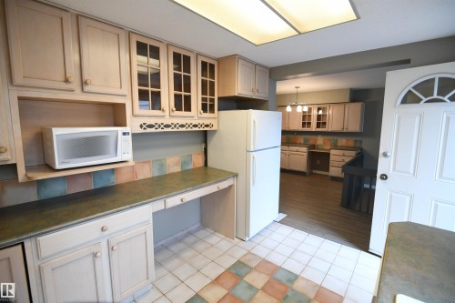 The shaker maple kitchen has loads of cabinet and counter space, and matches the extra cabinetry in the dining area.  Glass doors, ceramic tile, a writing desk, as well as an additional access to the rear yard and deck - 6706 36A Avenue, Edmonton, AB - Indoor Photo Showing Kitchen