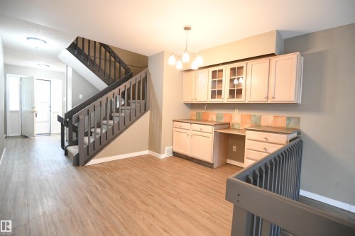 The open main floor is inviting, and lives large.  With plenty of space for a family sized dining table and open railings defining the space, this layout keeps the family together and engaged with each other.  Additional cabinetry matches the kitchen - 6706 36A Avenue, Edmonton, AB - Indoor Photo Showing Other Room