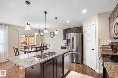 Kitchen island with integrated double basin sink and a granite countertop - 6864 Evans Wynd, Edmonton, AB - Indoor Photo Showing Kitchen With Stainless Steel Kitchen With Double Sink With Upgraded Kitchen