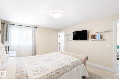 Carpeted interior room featuring a ceiling-mounted light fixture, light-colored walls, and white trim - 6864 Evans Wynd, Edmonton, AB - Indoor Photo Showing Bedroom
