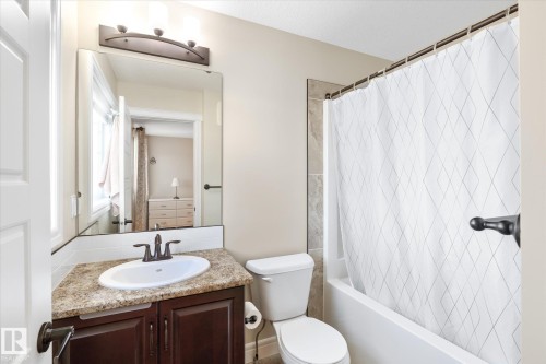 Bathroom featuring a dark wood vanity with a light-colored countertop, an undermount sink, and dark bronze fixtures - 6864 Evans Wynd, Edmonton, AB - Indoor Photo Showing Bathroom