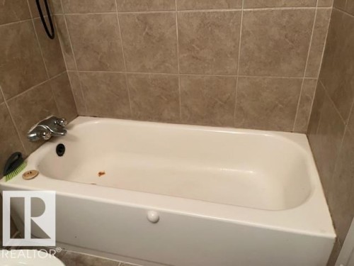 White built-in bathtub with chrome fixtures and light-toned square wall tiles - 6117 120 Avenue, Edmonton, AB - Indoor Photo Showing Bathroom