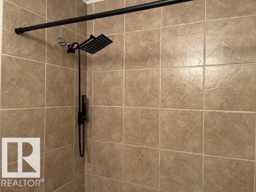 Tiled shower enclosure featuring a matte black rainfall showerhead with an integrated handheld sprayer - 6117 120 Avenue, Edmonton, AB - Indoor Photo Showing Bathroom