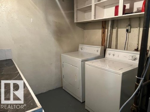 Dedicated laundry area featuring a washer and dryer, painted concrete flooring, and overhead open shelving - 6117 120 Avenue, Edmonton, AB - Indoor Photo Showing Laundry Room