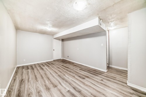 Spacious room featuring wood-finish flooring, light grey walls, white trim, and overhead lighting - 6117 120 Avenue, Edmonton, AB - Indoor Photo Showing Other Room