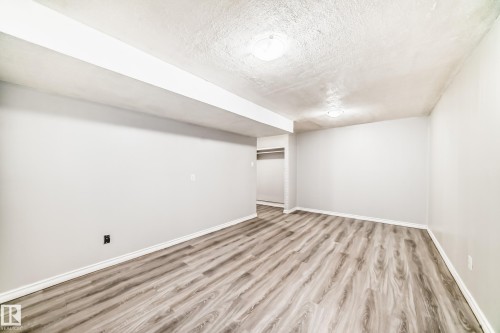 Spacious room featuring wood-finish flooring, light gray walls, white baseboards, and overhead dome lighting - 6117 120 Avenue, Edmonton, AB - Indoor Photo Showing Other Room