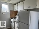 Kitchen featuring white cabinetry with dark hardware, a white refrigerator, a white electric range, and a tiled backsplash - 6117 120 Avenue, Edmonton, AB  - Indoor Photo Showing Kitchen 
