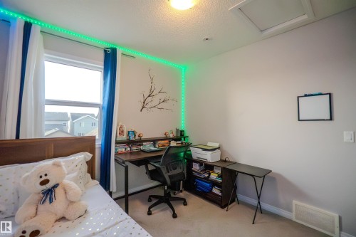 Bright room featuring a window with white and blue curtains, light-toned carpeting, and a built-in ceiling light - 1766 Dumont Crescent Sw, Edmonton, AB - Indoor