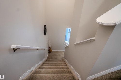 Carpeted staircase featuring a light neutral wall color, white handrail, and white trim - 1766 Dumont Crescent Sw, Edmonton, AB - Indoor Photo Showing Other Room