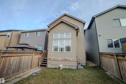 Rear exterior featuring tan siding, a multi-pane window configuration, and a raised wooden deck with stairs - 1766 Dumont Crescent Sw, Edmonton, AB - Outdoor With Exterior
