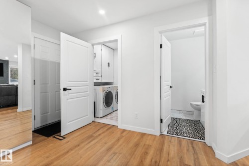 Laundry area with built-in cabinetry, stacked appliances, wood-finish flooring, recessed lighting, and a solid core door - 362 Blackburn Drive E, Edmonton, AB - Indoor Photo Showing Laundry Room