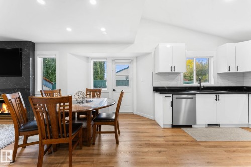 Open-concept living area featuring wood-finish flooring, a contemporary fireplace with a dark stone surround, recessed lighting, and vaulted ceilings - 362 Blackburn Drive E, Edmonton, AB - Indoor
