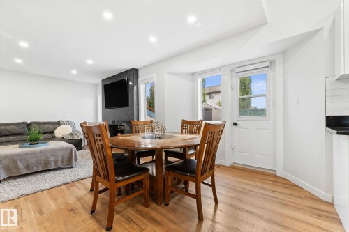 Open-concept living space featuring wood-finish flooring, recessed lighting, and a dark stone fireplace surround - 362 Blackburn Drive E, Edmonton, AB - Indoor Photo Showing Dining Room