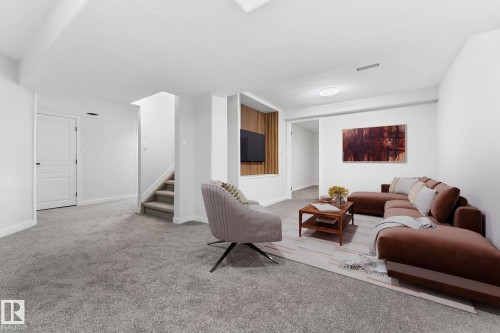 Spacious finished room featuring light gray carpeting, white painted walls, and a recessed wood-paneled media niche - 362 Blackburn Drive E, Edmonton, AB - Indoor