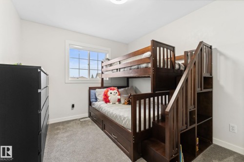 Bedroom featuring a large window with white trim, light gray carpet flooring, and a ceiling-mounted light fixture - 362 Blackburn Drive E, Edmonton, AB - Indoor Photo Showing Bedroom