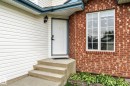 Exterior showcasing a brick facade, white siding, a white entry door with a smart lock, concrete steps, and a double-pane window with grid inserts - 362 Blackburn Drive E, Edmonton, AB  - Outdoor With Exterior 