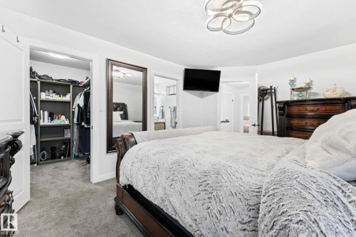 Carpeted bedroom featuring a contemporary ceiling light fixture, a built-in closet with shelving, a full-length mirror, and a wall-mounted flat-screen television - 362 Blackburn Drive E, Edmonton, AB - Indoor Photo Showing Bedroom